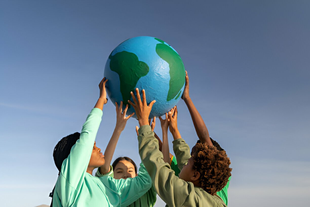 Children holding up a globe together, symbolizing the global effort required for Zero Waste Living and environmental sustainability.