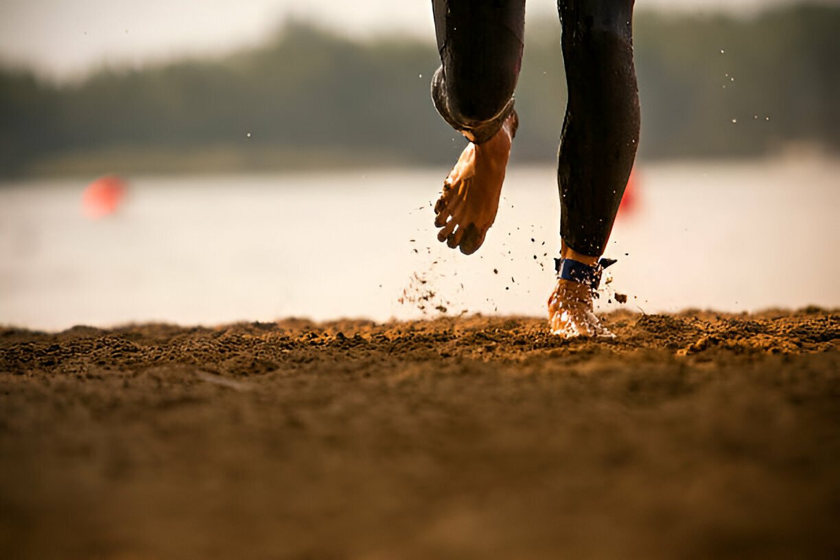 Close-up of feet during a Barefoot Running session on a sandy beach.