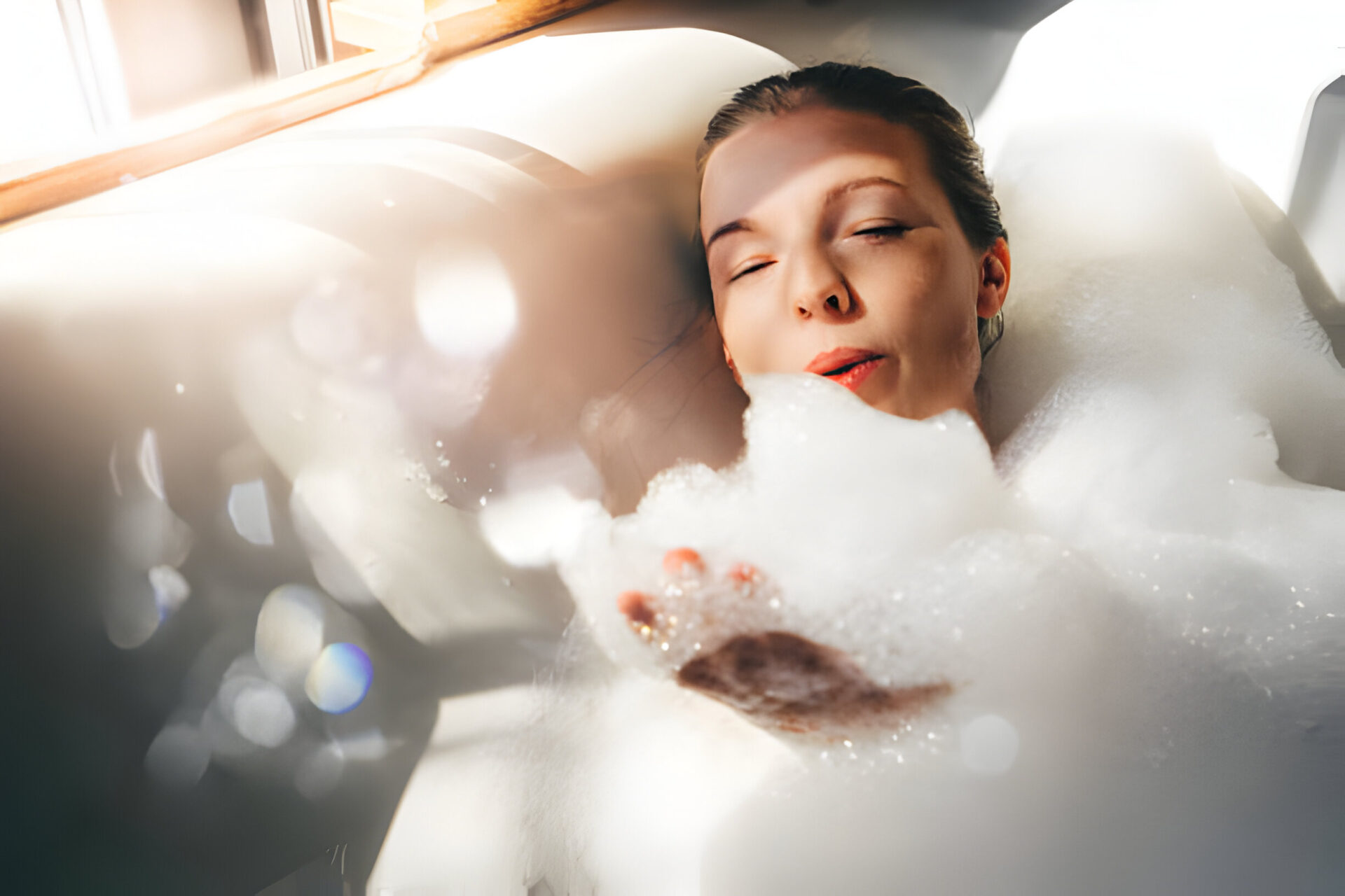 A woman enjoying a relaxing bubble swim spa bath, with sunlight streaming in through a nearby window.