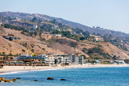 Scenic view of Malibu coastline, a popular area in Southern California affected by the recent earthquake Los Angeles, highlighting beachfront homes and nearby hills.